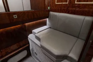 The dedicated crew rest area or jumpseat in the Falcon 50EX, featuring gray leather upholstery and high-gloss wood paneling
