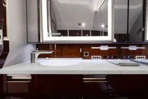 Close-up detail of the modern sink, faucet, and white countertop in the aft lavatory of the Falcon 50EX